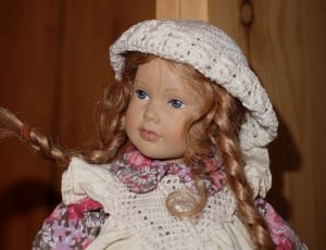 girl in white and pink floral dress with white knit cap doll thumbnail