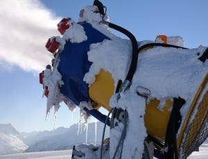 close photo of yellow and blue machine filled with snow thumbnail