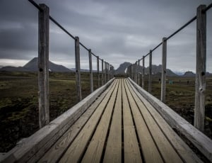 brown wooden footbridge near mountains thumbnail