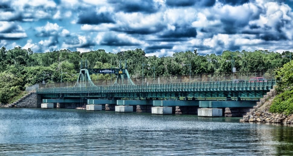 green concrete bridge under body of water under cloudy sky preview