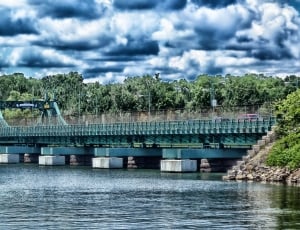 green concrete bridge under body of water under cloudy sky thumbnail