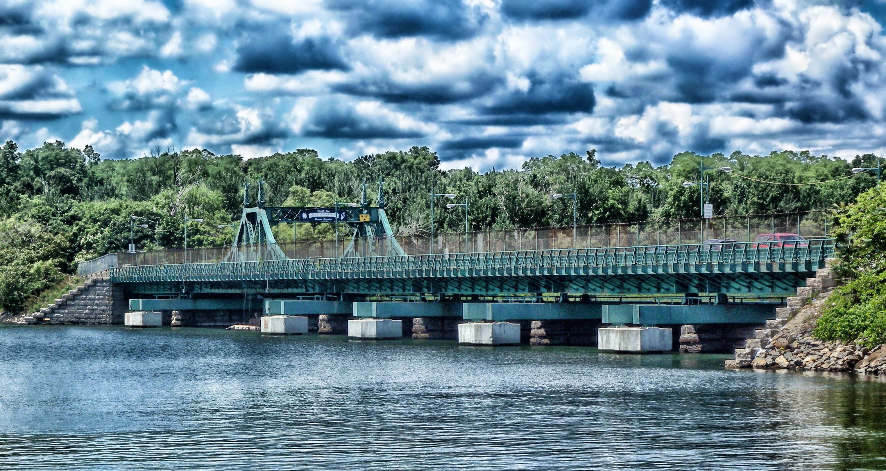 green concrete bridge under body of water under cloudy sky