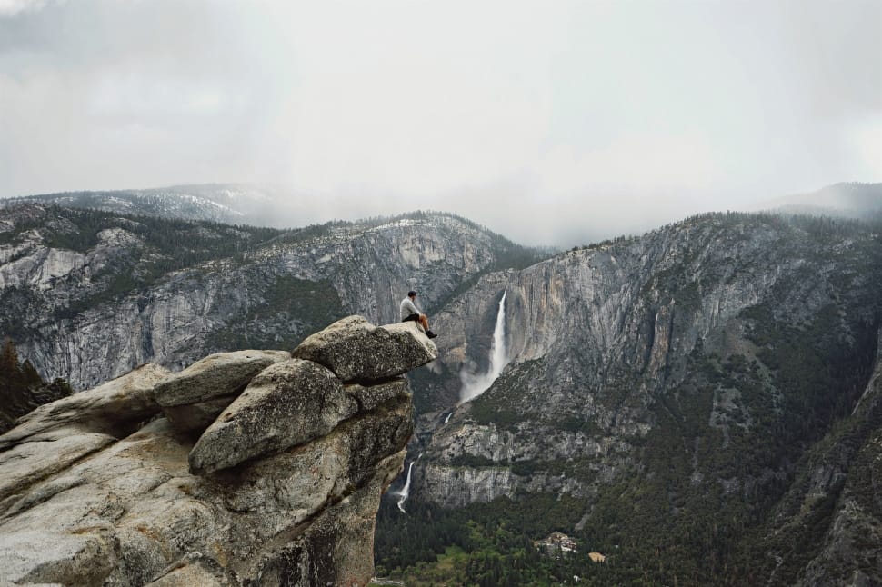 man sitting in edge of cliff photograph preview
