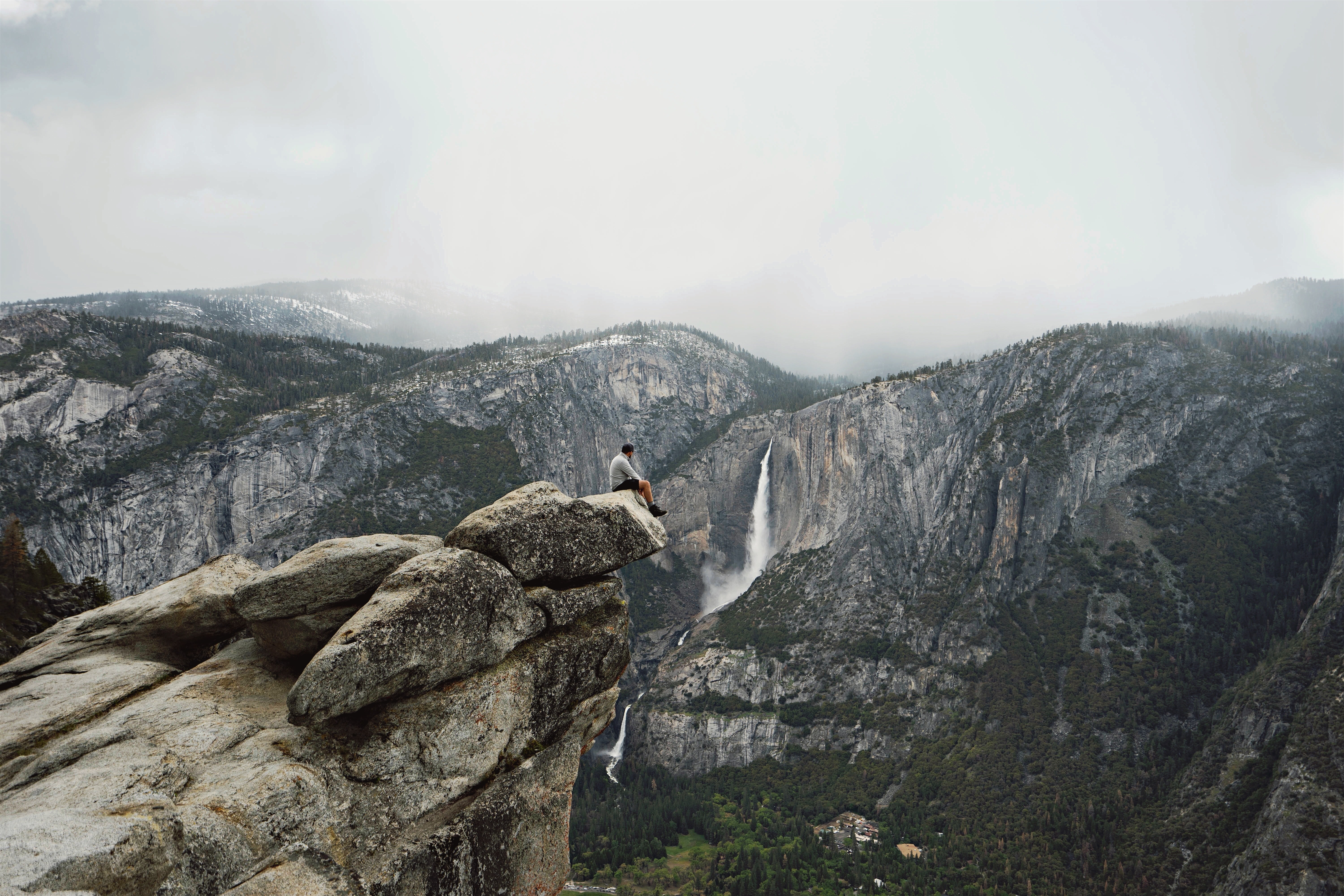 man sitting in edge of cliff photograph