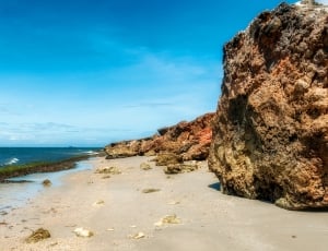 seashore near rocks under blue sky during daytime thumbnail
