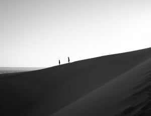 black and white picture of two person walking through mountain dessert thumbnail