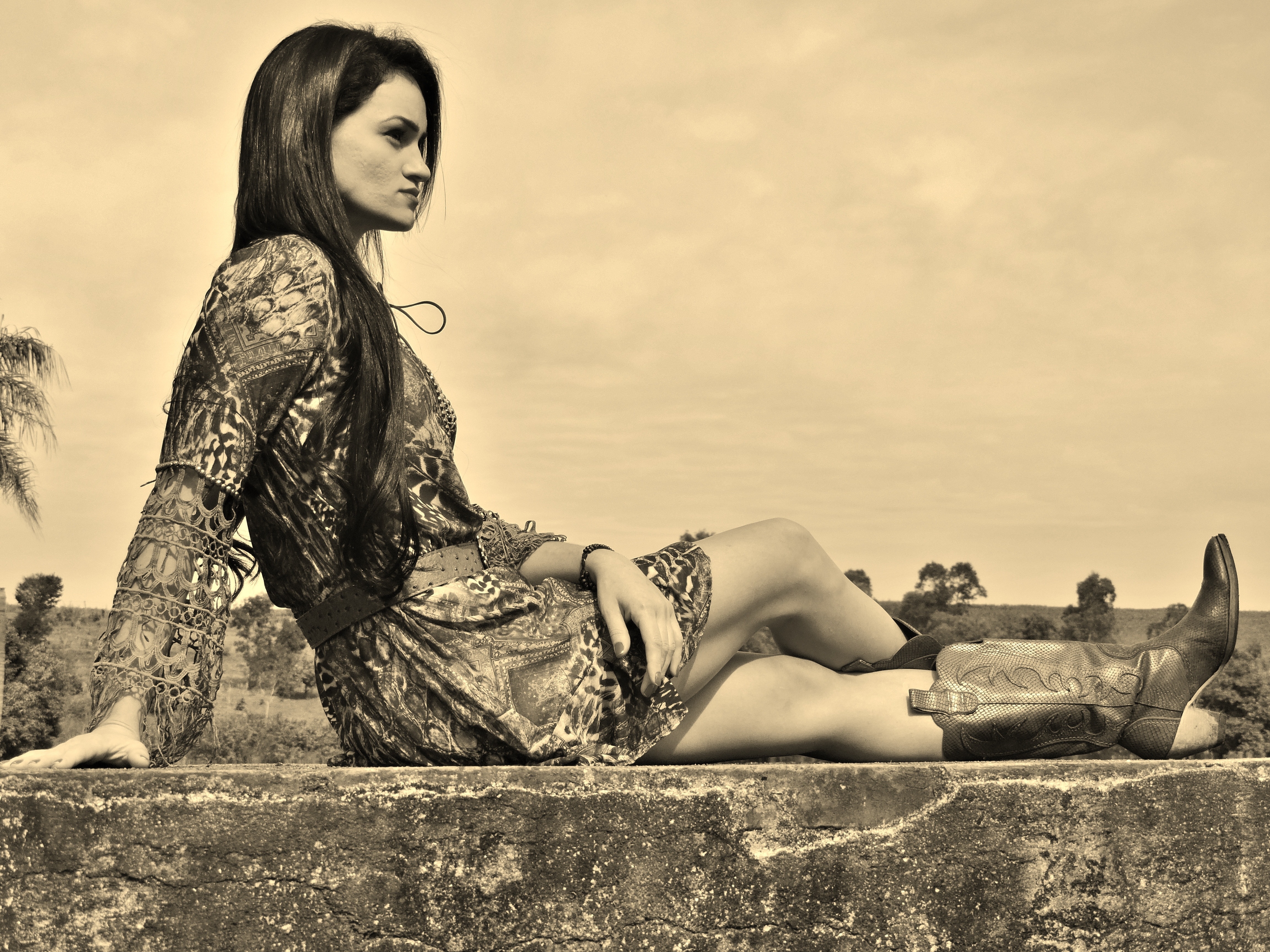 greyscale photo of woman in long sleeve dress and cowboy boots