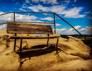 brown wooden bench on sand during day time thumbnail