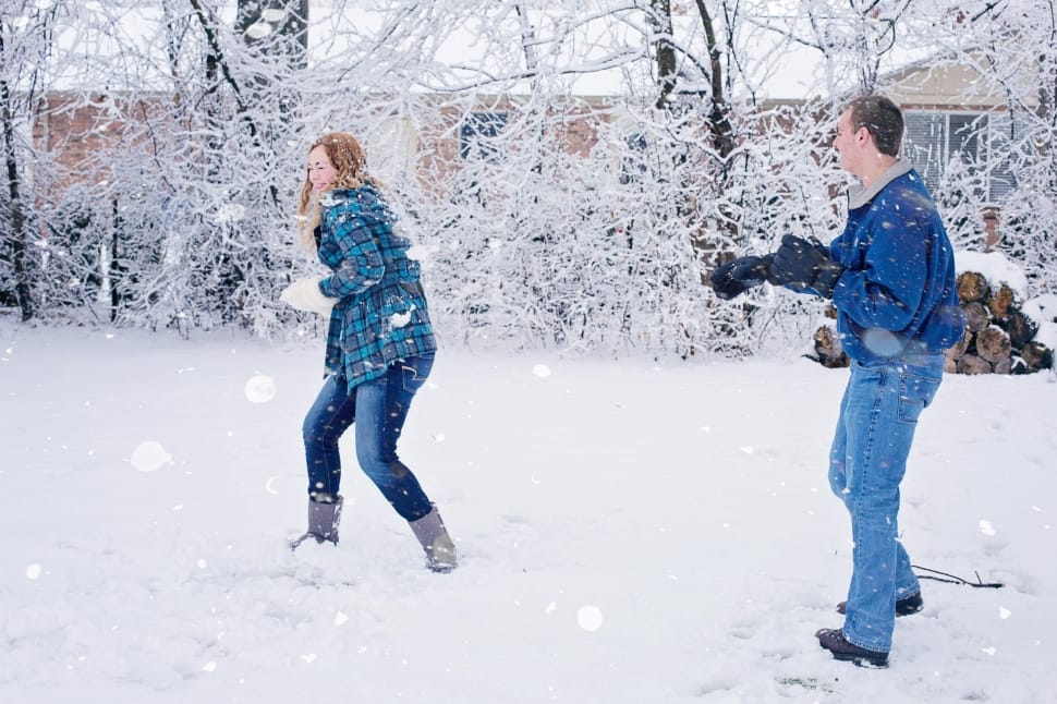 couple with jacket throwing a snowball to each other during daytime preview