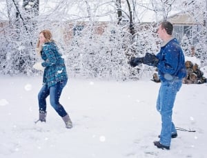 couple with jacket throwing a snowball to each other during daytime thumbnail