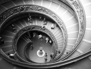 group of people walking on spiral staircase in gray scale photography thumbnail