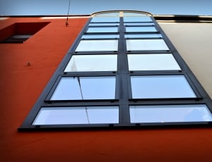 black window pane with red and white painted building during daytime thumbnail