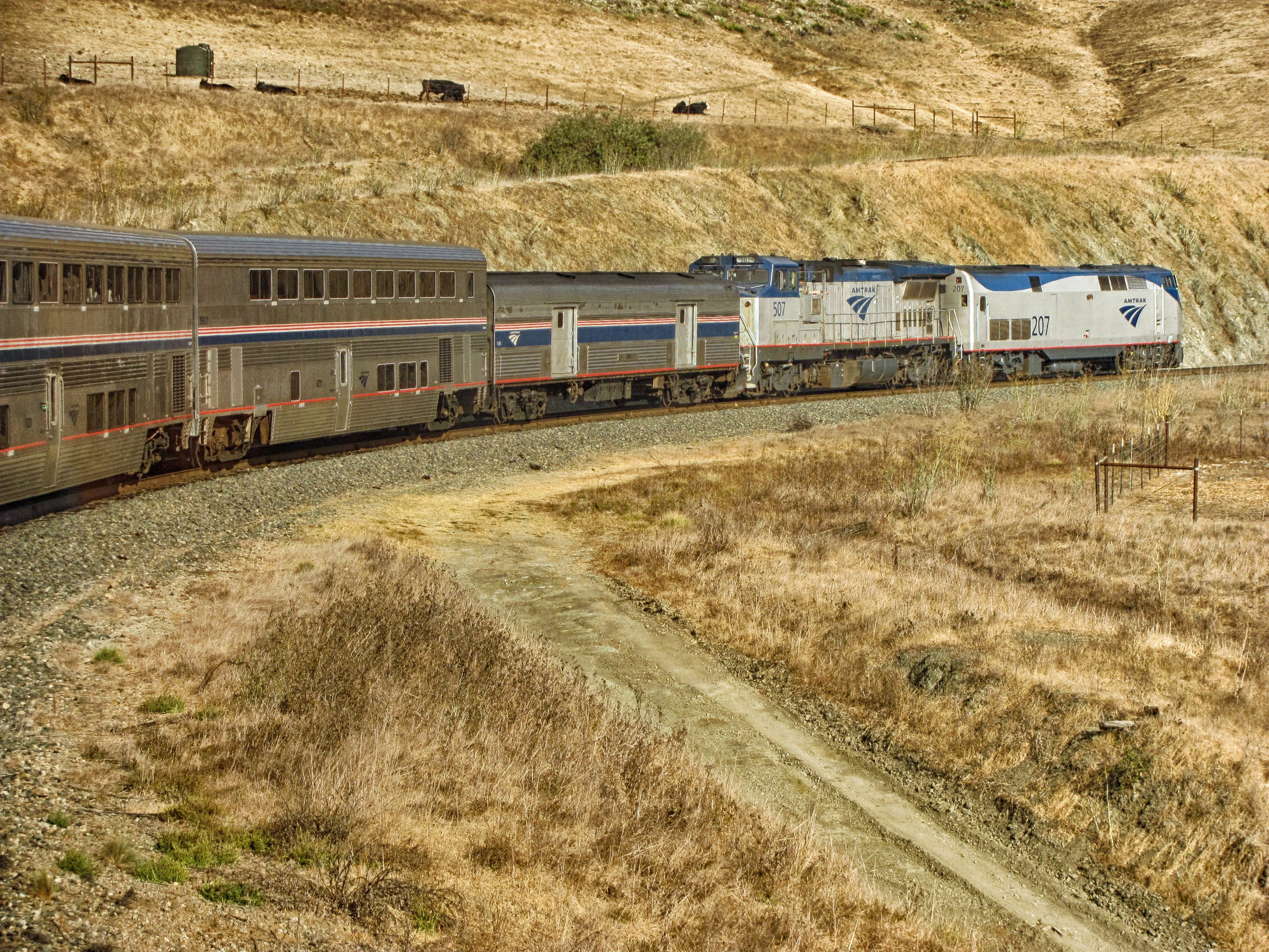 photo of grey and white train near brown sod grass