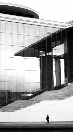 person walking beside concrete building in gray scale photography thumbnail