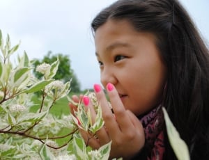 girl in black jacket near white flowers during daytime thumbnail