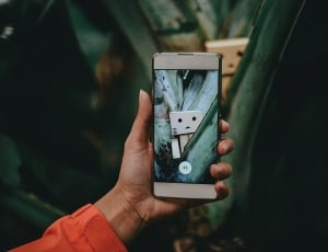 human hand holding white android smartphone thumbnail