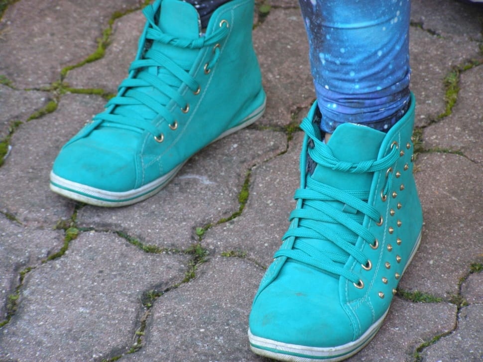 pair of teal high top sneakers with gold spike studs on human feet preview