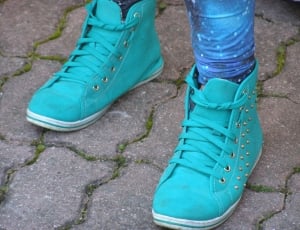 pair of teal high top sneakers with gold spike studs on human feet thumbnail