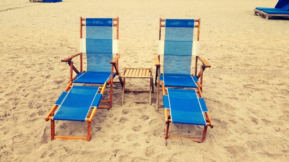 two brown wooden frame blue and white adirondack chair on sand preview