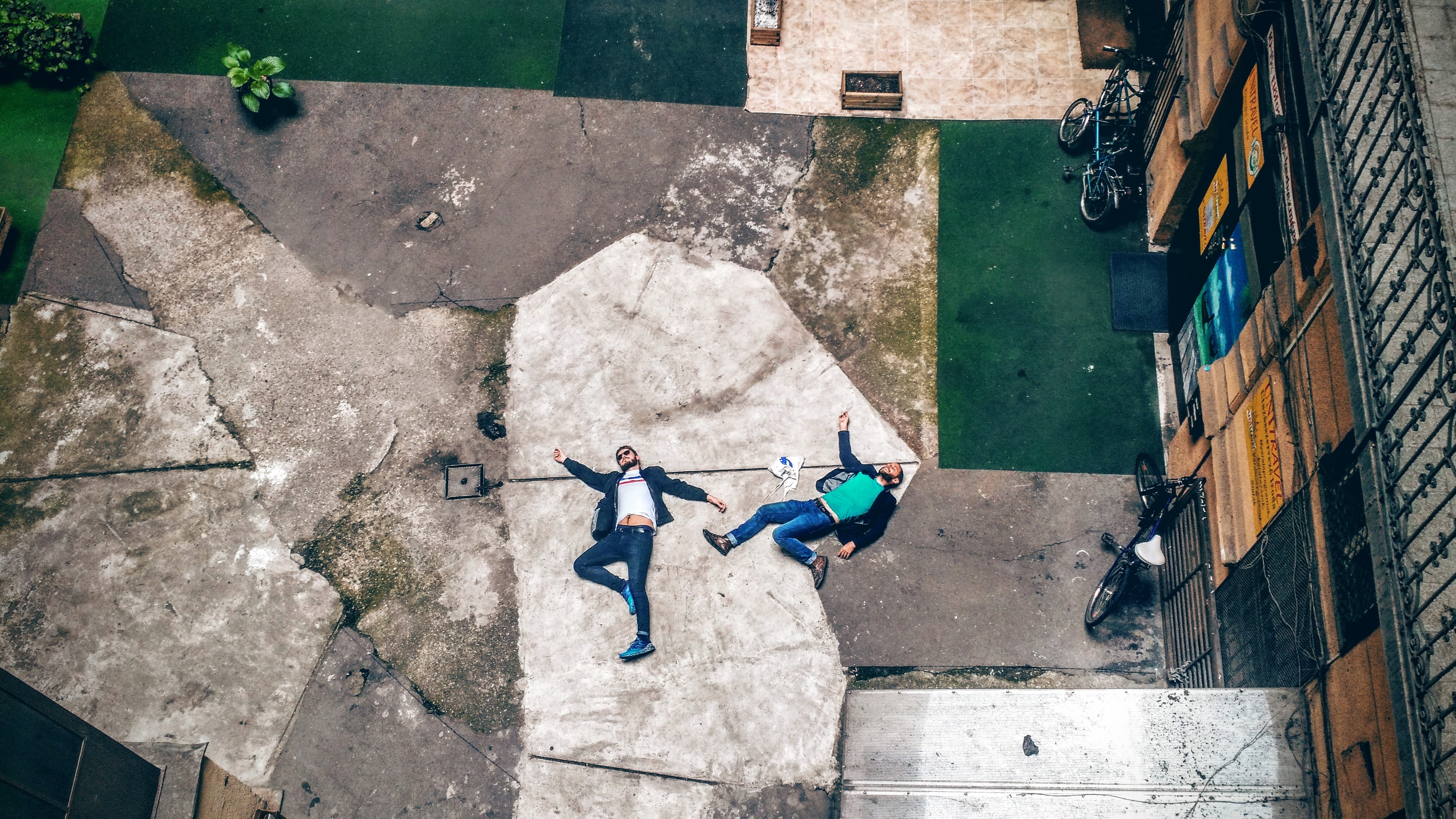 two man lying down on concrete path
