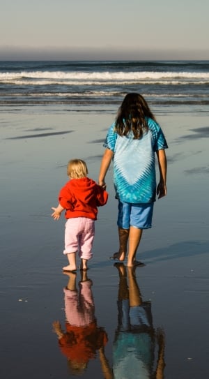 woman and boy walking on seashore during daytime thumbnail