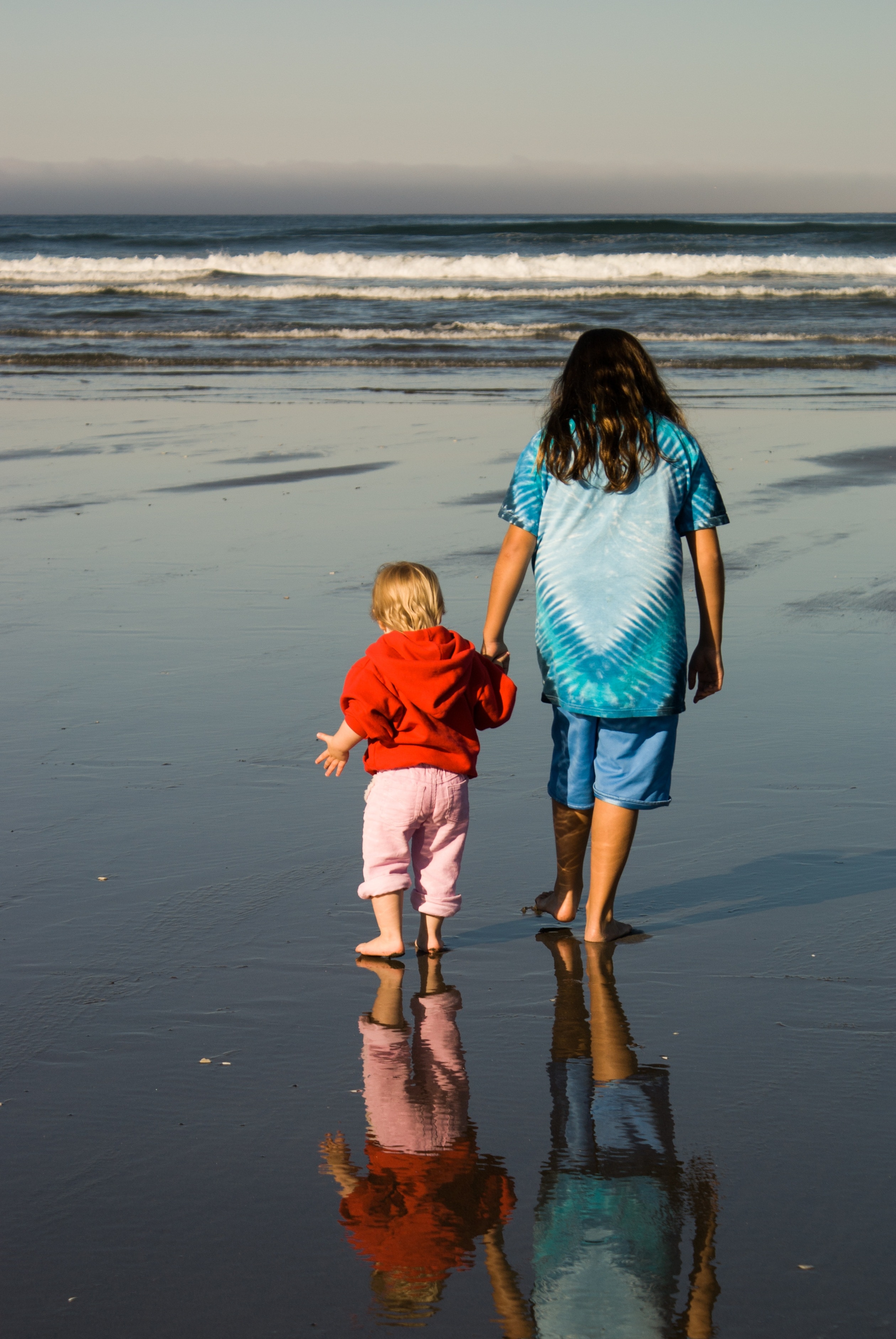 woman and boy walking on seashore during daytime