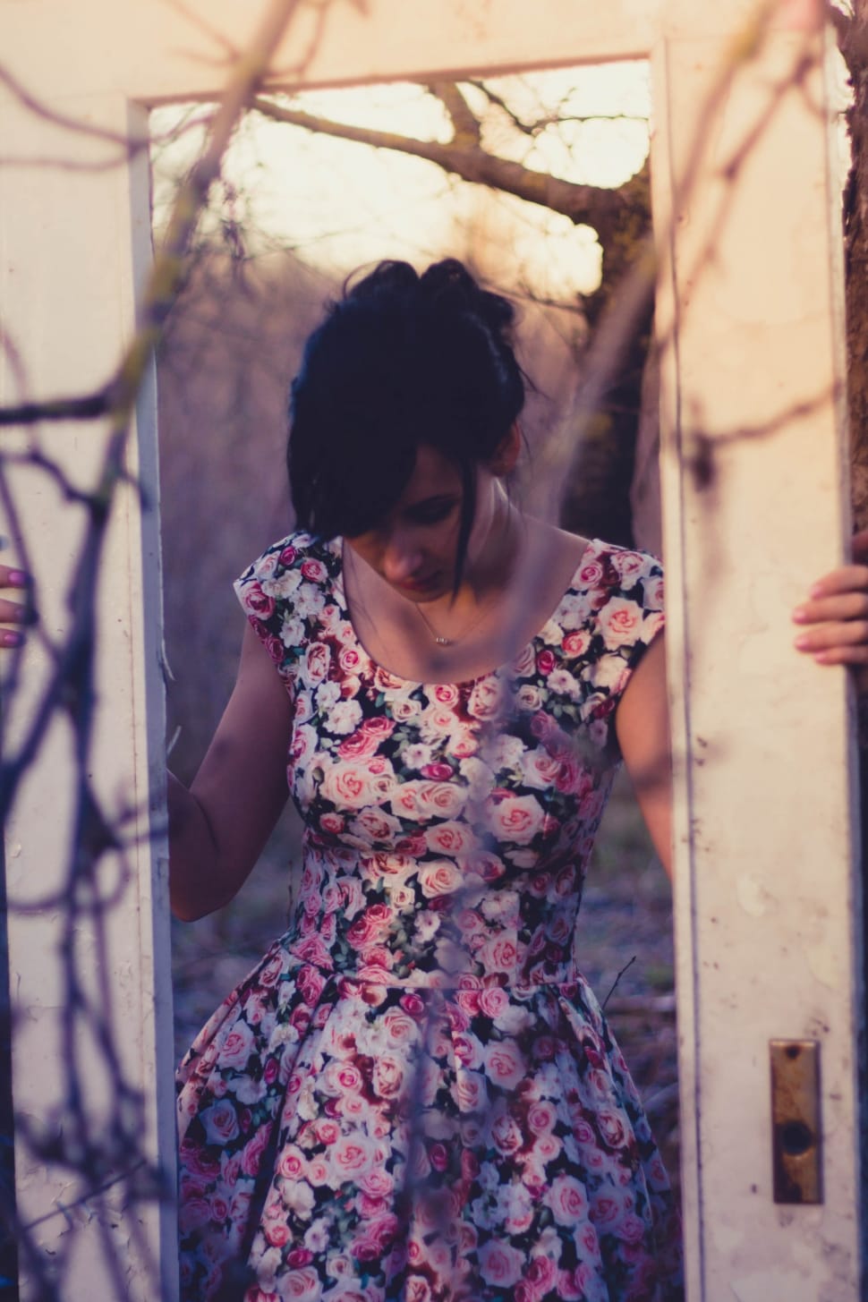 woman wearing pink black and red floral scoop neck dress holding door frame preview