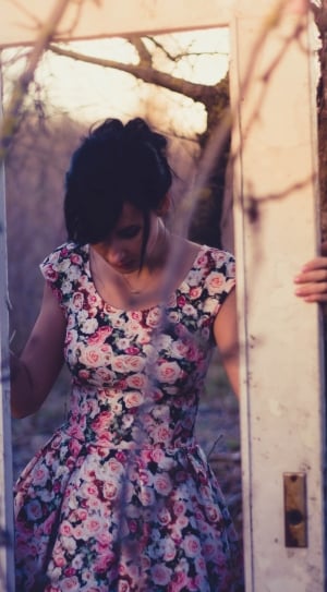woman wearing pink black and red floral scoop neck dress holding door frame thumbnail