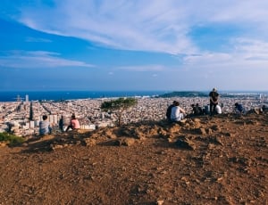 group of people on cliff side with city view during daytime thumbnail