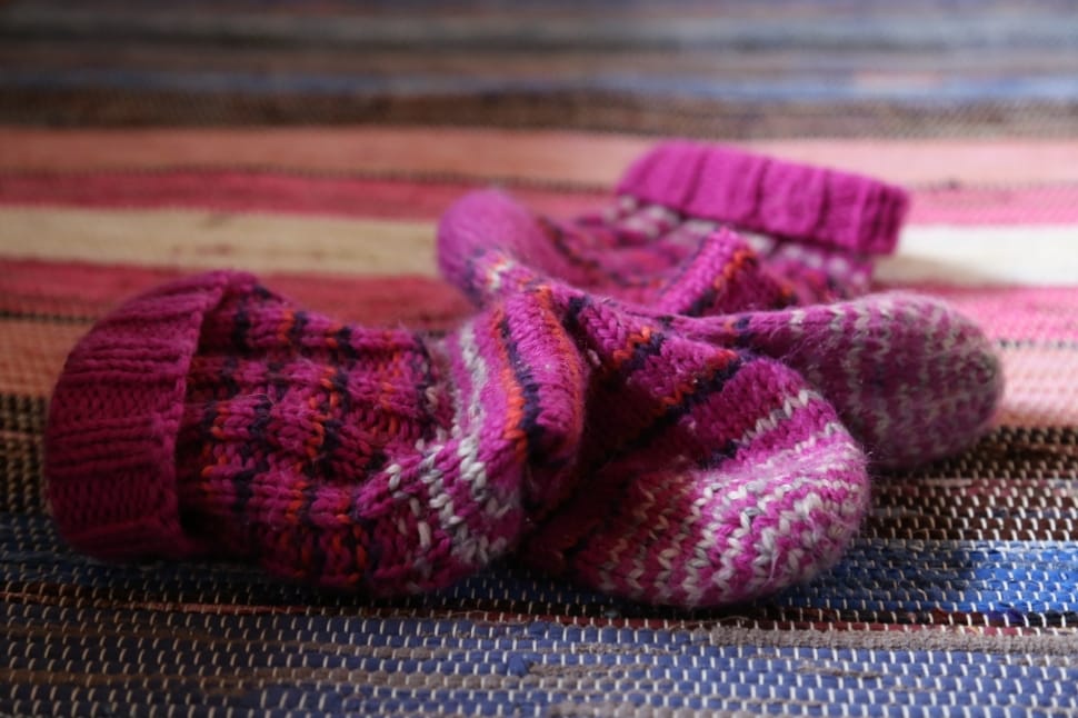 toddler's pink knitted sock on multicolored surface preview