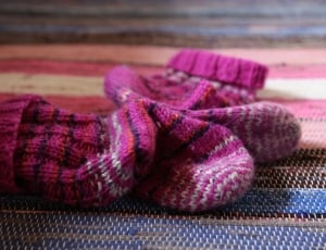 toddler's pink knitted sock on multicolored surface thumbnail