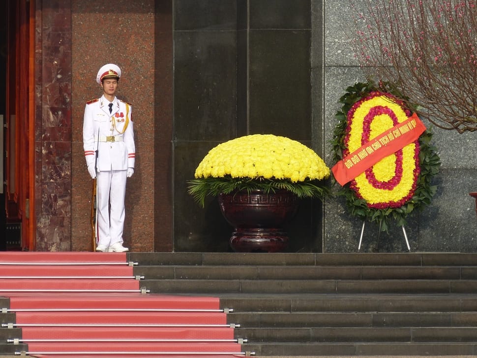 men's white military uniform near yellow flower decoration during daytime preview