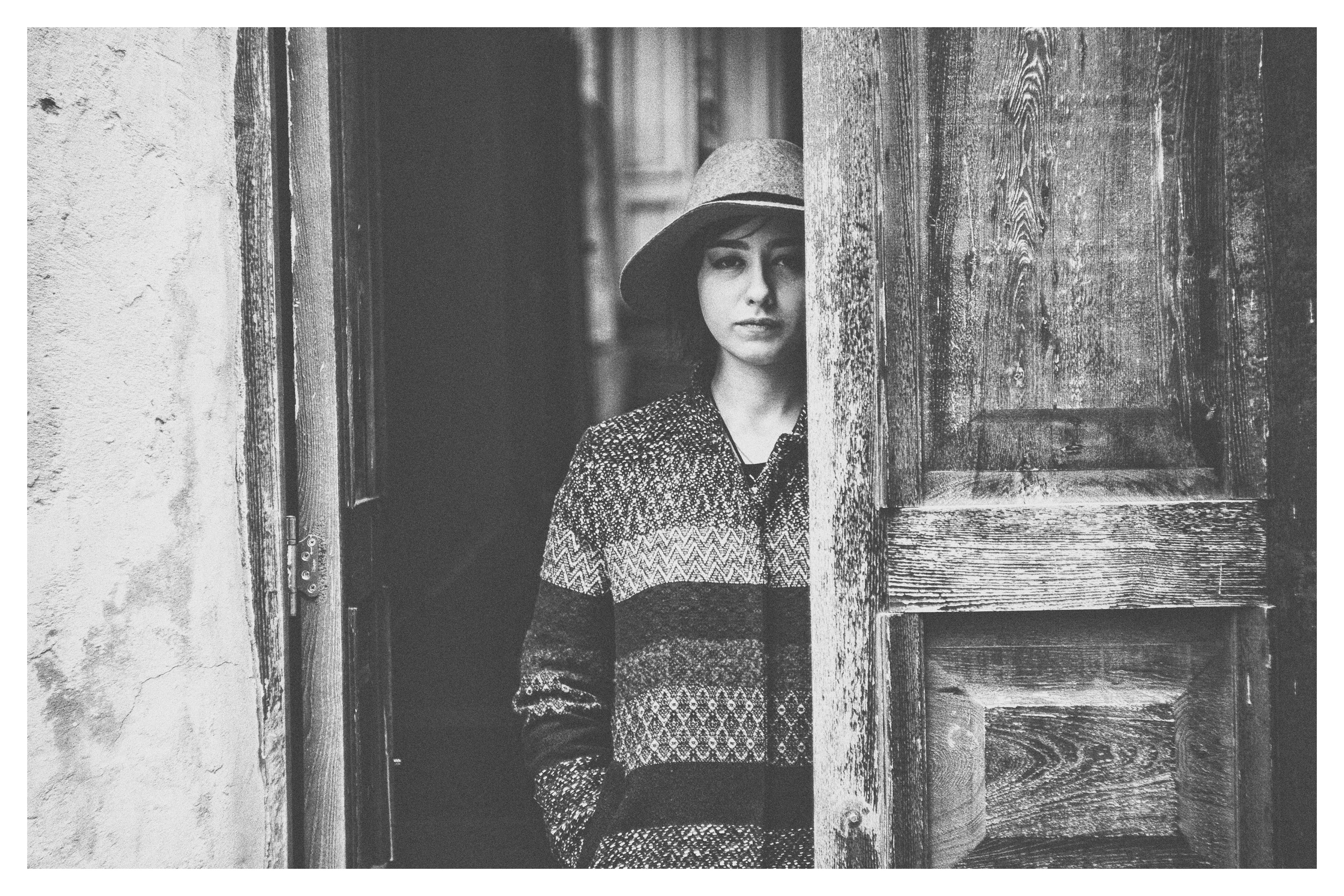 greyscale photo of woman behind door