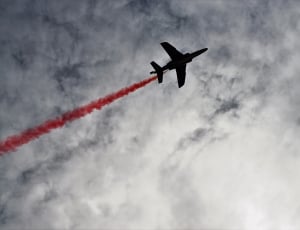 plane leaving red contrail on sky during daytime thumbnail