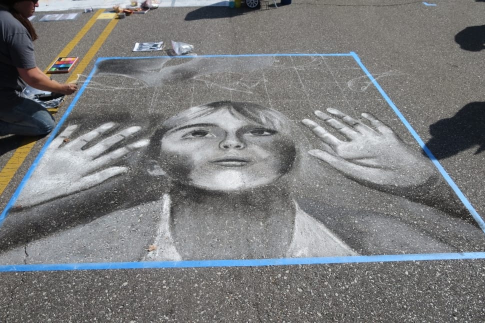 person painting the road with child looking up and raising hands during daytime preview
