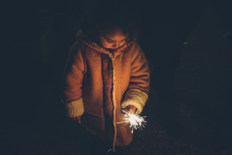 girl in brown jacket holding sparkles fireworks preview