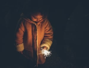 girl in brown jacket holding sparkles fireworks thumbnail