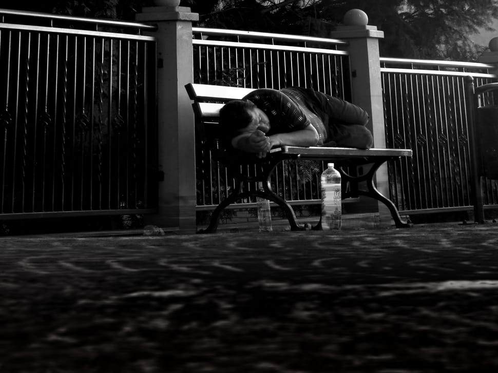 man in black shirt sleeping on brown wooden bench during daytime preview