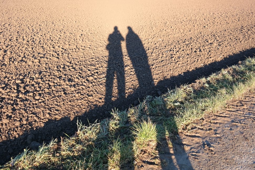 two shadows of two person standing side by side during day preview