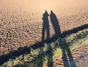 two shadows of two person standing side by side during day thumbnail