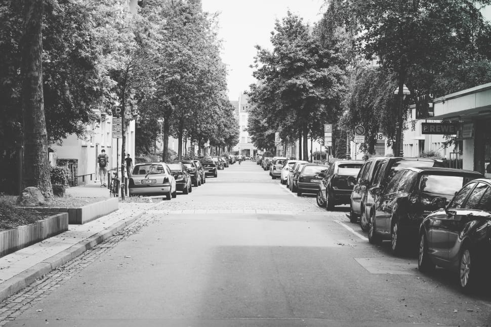 grayscale photography of pathway with many car at the side preview