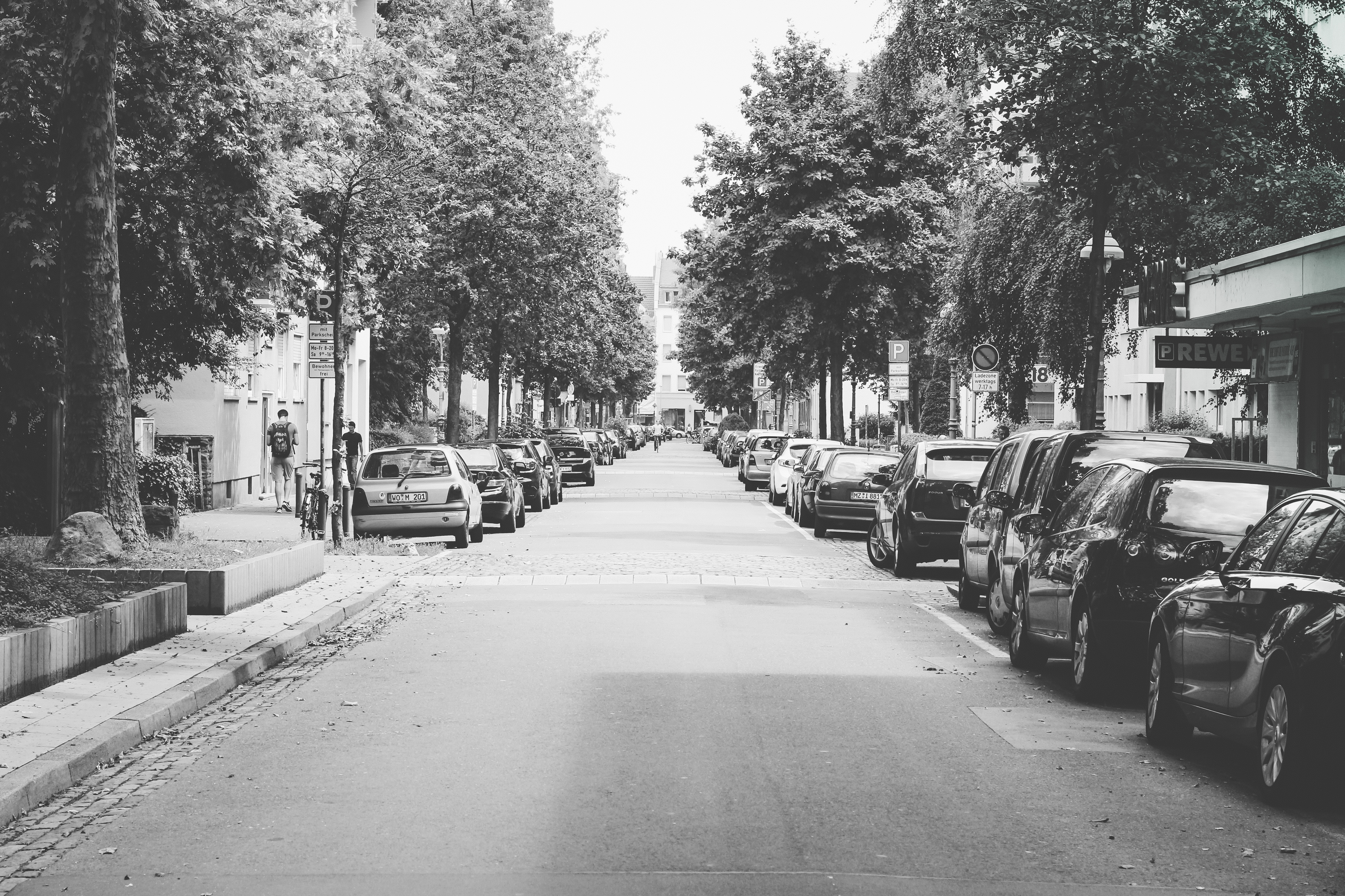 grayscale photography of pathway with many car at the side