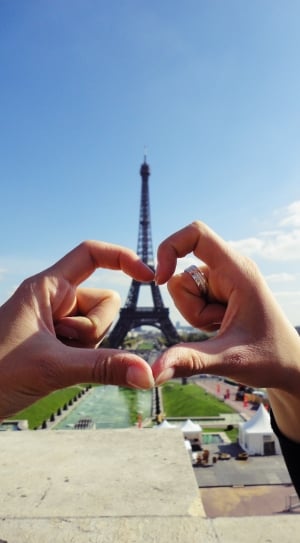 persons hand showing heart shaped in front of eiffel tower thumbnail