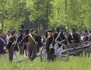 people at the field wearing uniforms with cannons during day thumbnail