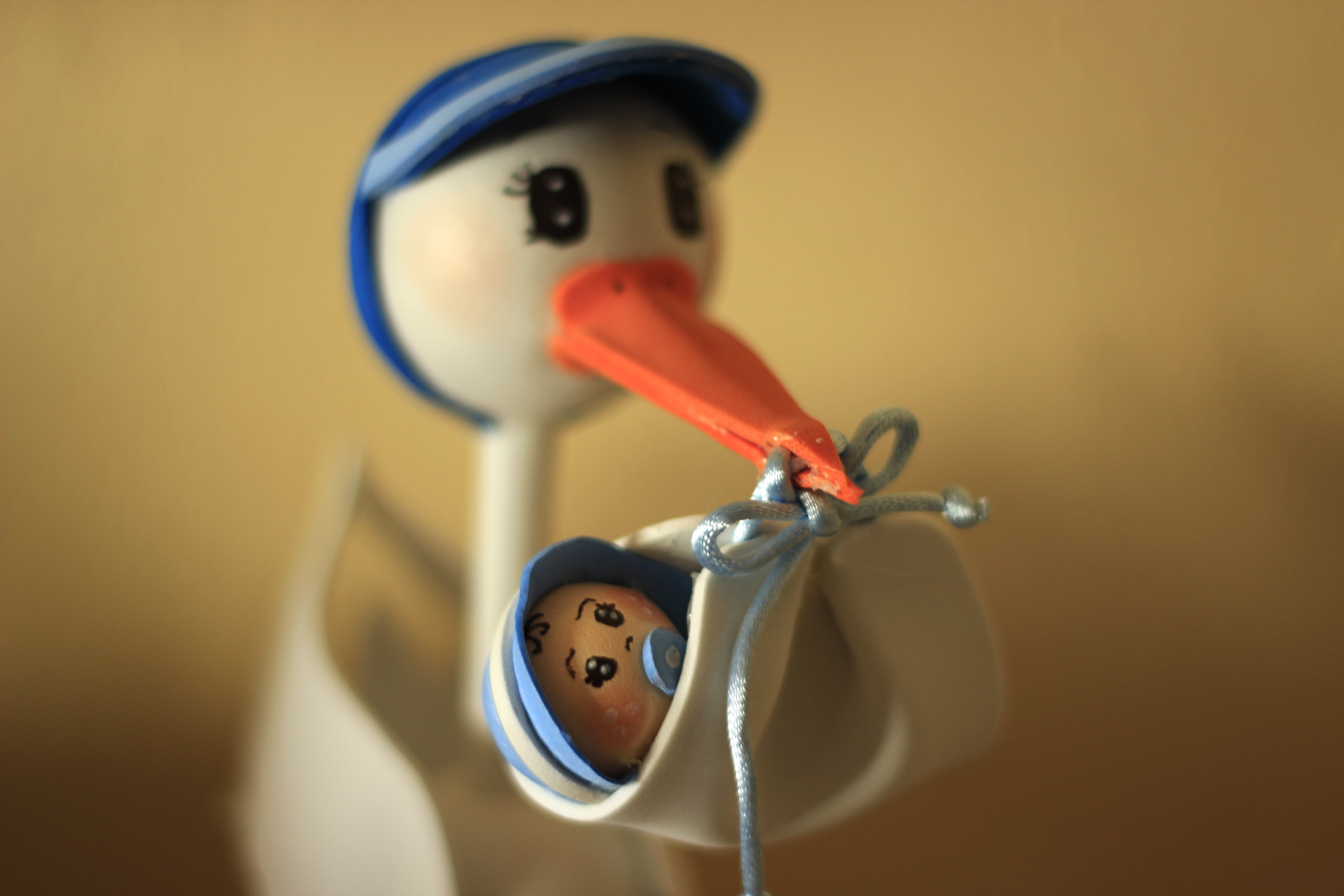 beige and blue bird carrying baby on his bill figurine