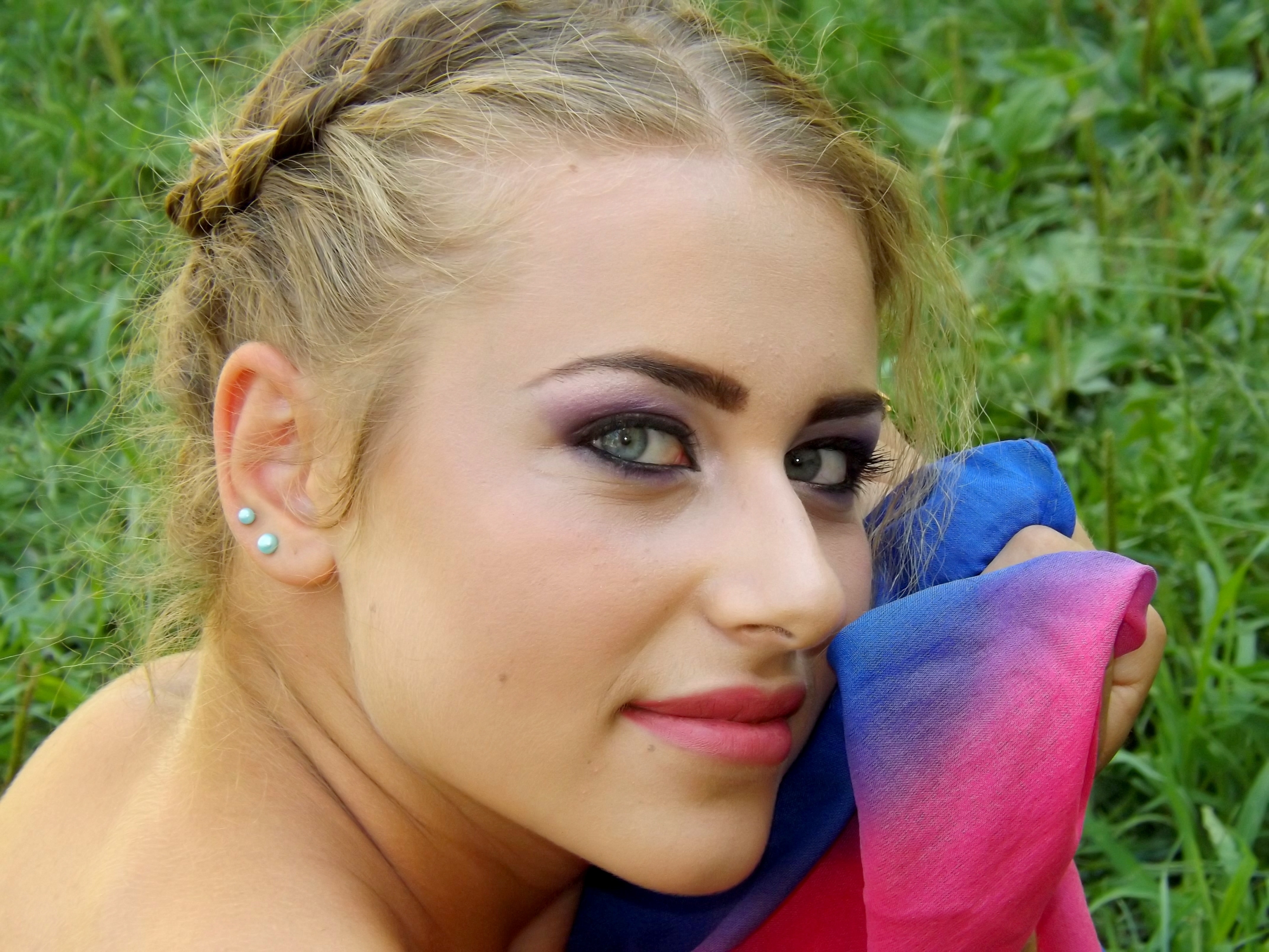 woman holding blue and pink towel with stud earrings