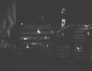 grayscale photo of man playing guitar with microphone thumbnail