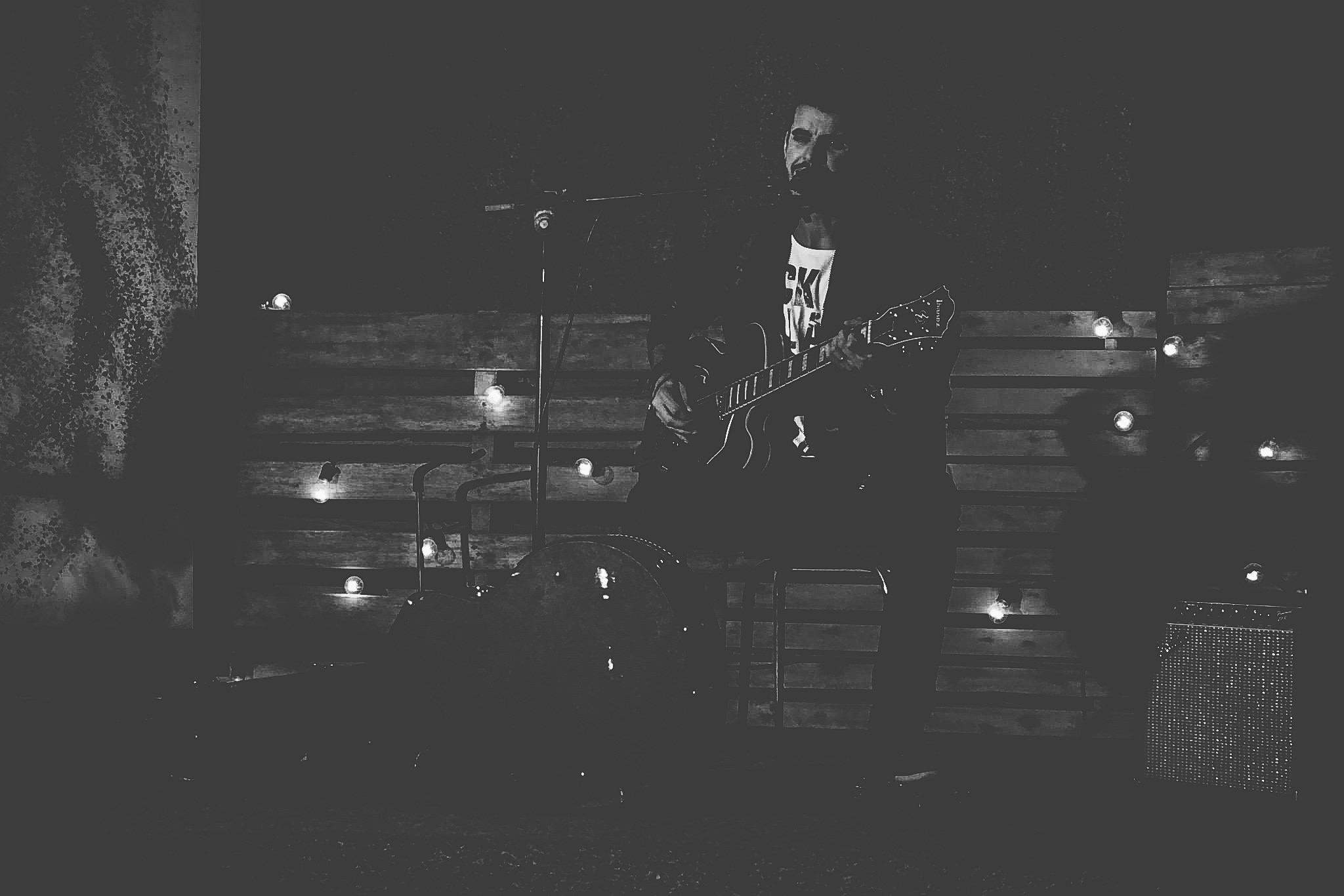 grayscale photo of man playing guitar with microphone