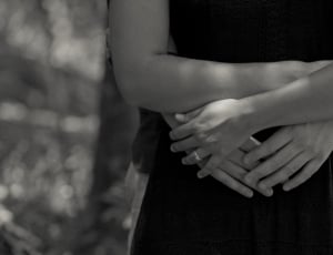 grayscale photo of person hugging woman wearing dress from the back thumbnail