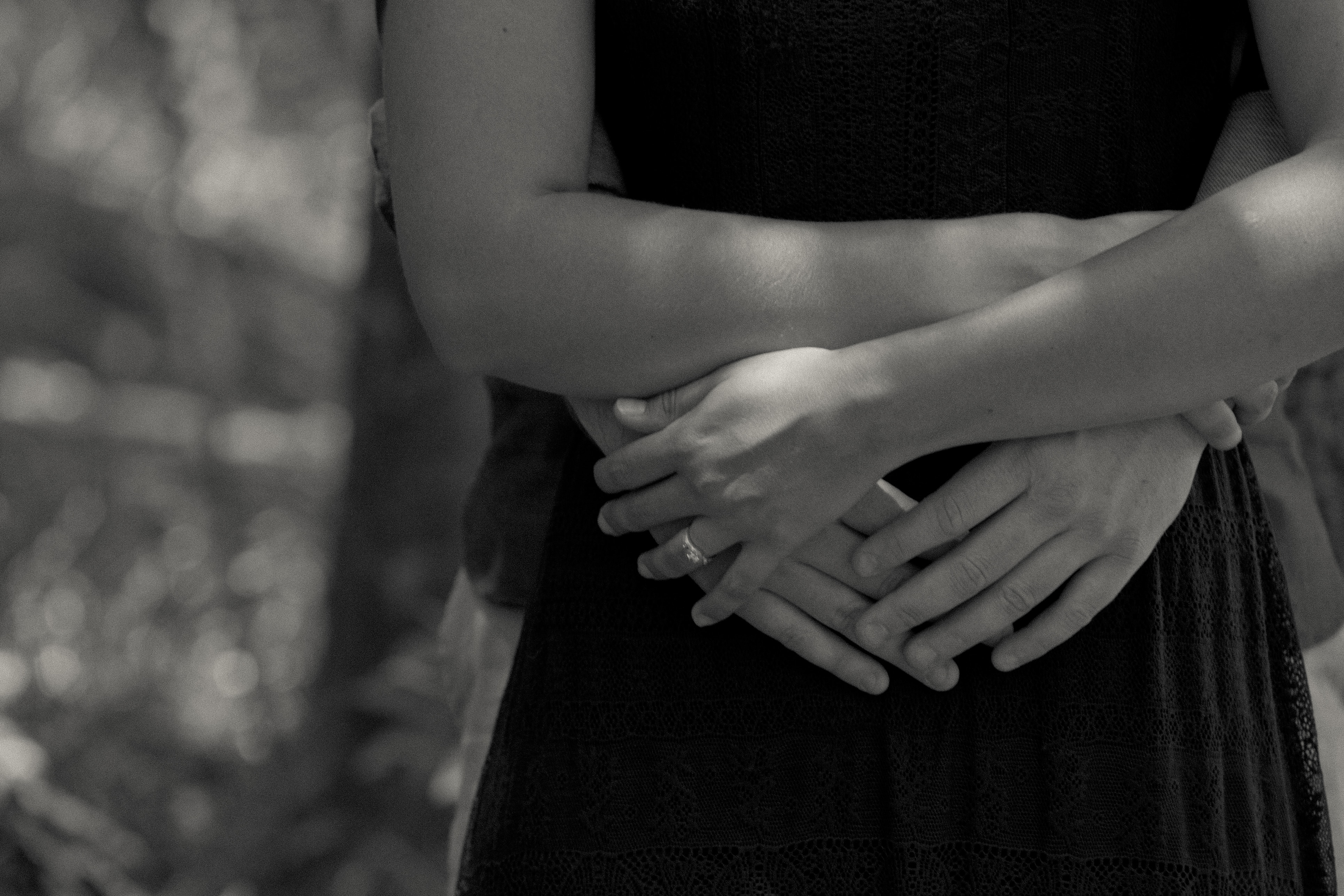 grayscale photo of person hugging woman wearing dress from the back